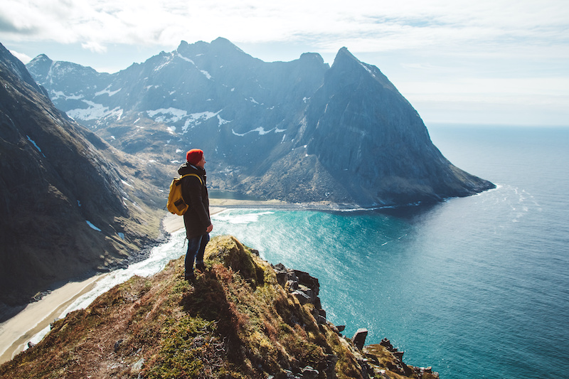 Man stand on cliff edge alone enjoying aerial view backpacking lifestyle travel adventure outdoor vacations.